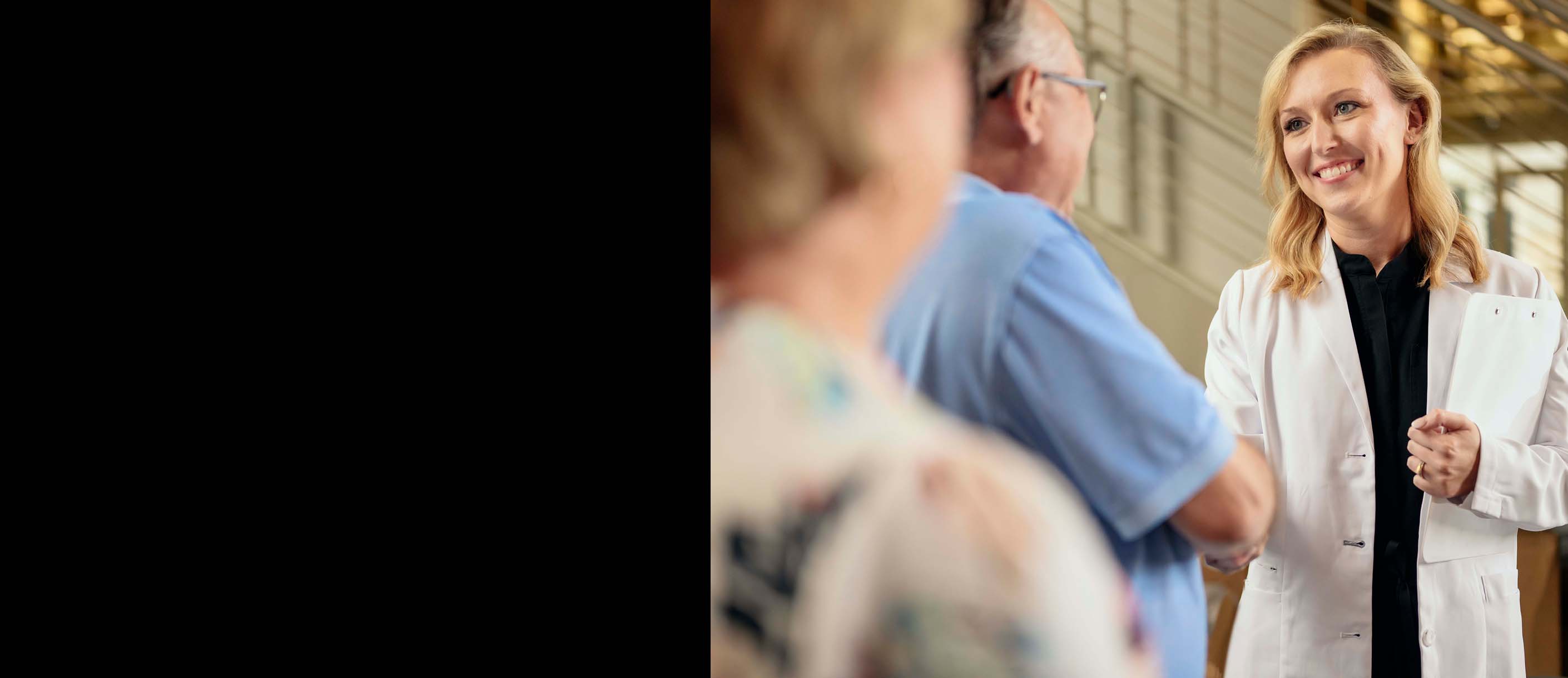 A man wearing hearing aids shaking hands with a female hearing professional