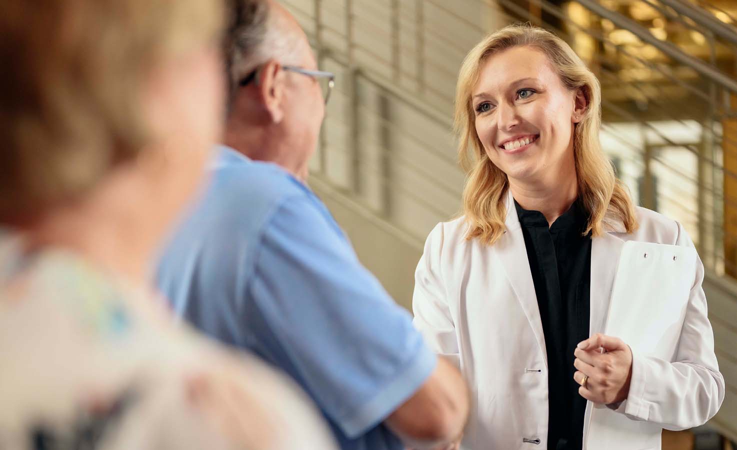A man wearing hearing aids shaking hands with a female hearing professional